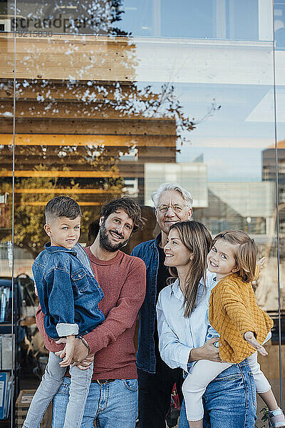 Familie steht zusammen vor einer Glaswand