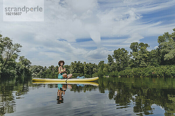 Junge Frau macht Yoga auf dem Paddleboard im See