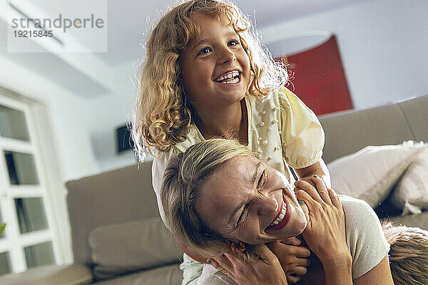 Glückliches Mädchen umarmt Mutter im Wohnzimmer