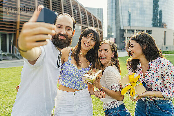 Lächelnder Mann  der mit Freunden ein Selfie per Smartphone macht