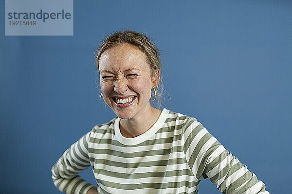 Frau lacht vor blauem Hintergrund