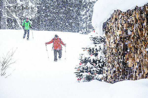 Älteres Paar beim Schneeschuhwandern in der Nähe von Brennholz im Schnee