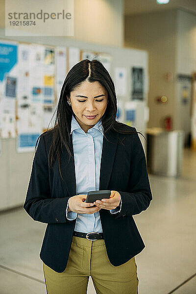 Schöne Geschäftsfrau benutzt Smartphone im Büro