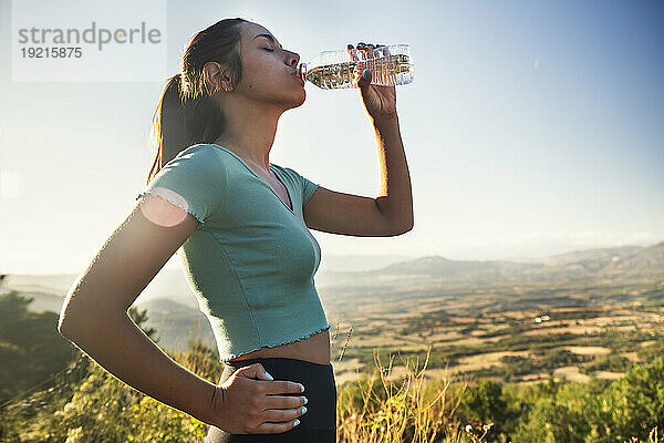 Durstige Frau trinkt Wasserflasche an einem sonnigen Tag