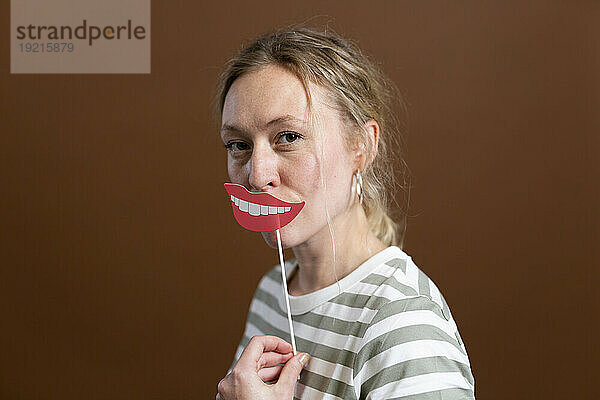 Blonde Frau hält Lippenstütze im Studio