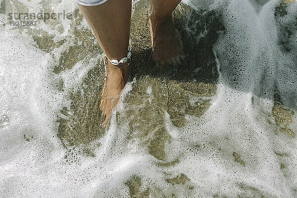 Füße einer Frau im Wasser am Strand
