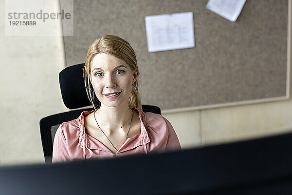 Lächelnde Geschäftsfrau sitzt im Büro