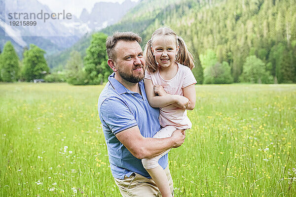 Smiling man with daughter walking amidst plants