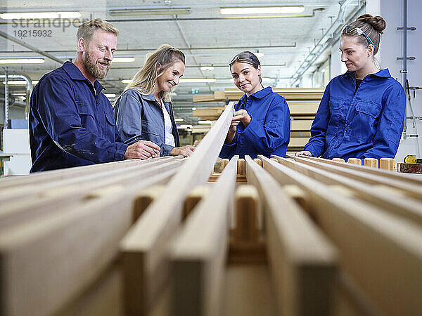 Lächelnder Auszubildender hält Holzbrett in der Fabrik