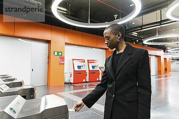 Junge Frau zieht Fahrkarte vom Automaten an der U-Bahn-Station
