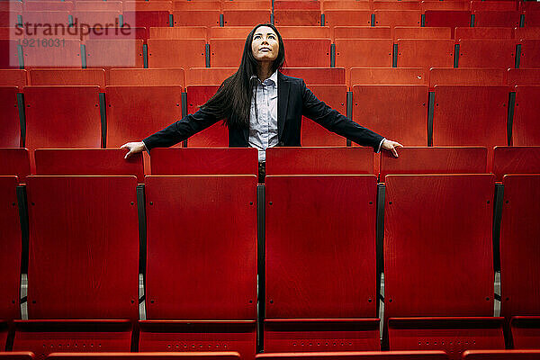 Businesswoman amidst red seats in convention center