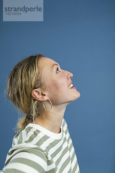 Smiling blond woman looking up against blue background
