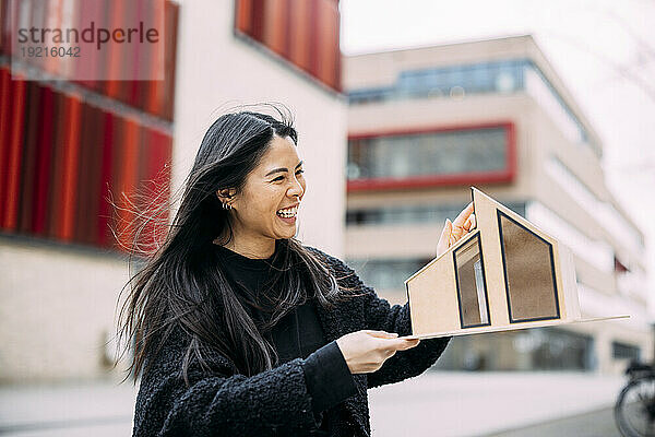 Cheerful architect examining house model outside office building