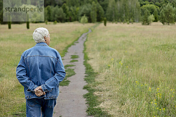 Älterer Mann spaziert auf Fußweg im Park