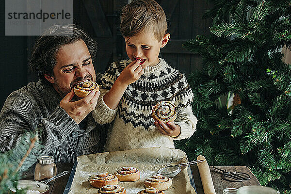 Vater und Sohn essen Zimtschnecken am Tisch