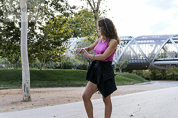 Frau mit Smartwatch steht im Park