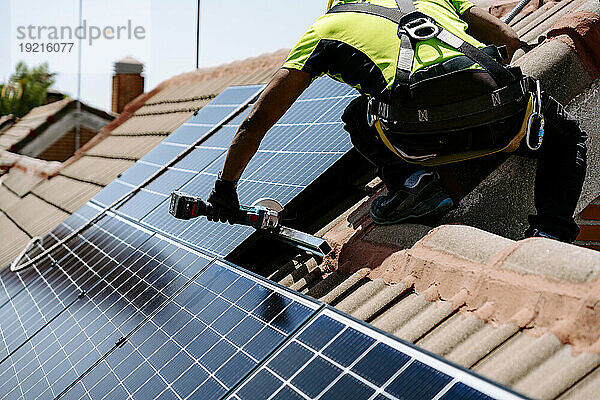 Ingenieur mit Handwerkzeug installiert Solarpanel an sonnigem Tag