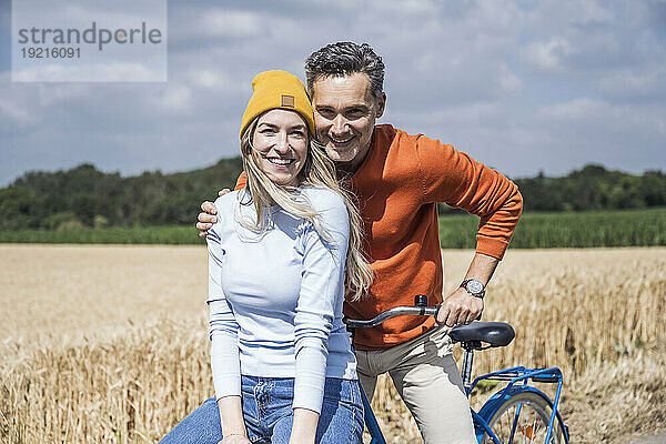 Glücklicher Mann und Frau mit Fahrrad auf dem Feld