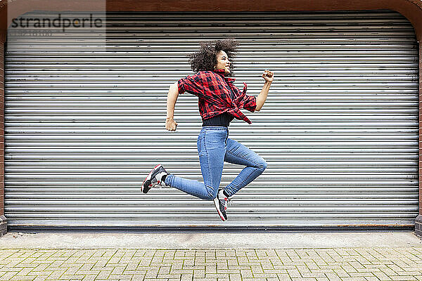 Smiling woman jumping in front of shutter