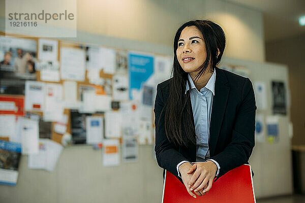 Smiling businesswoman leaning on chair at office