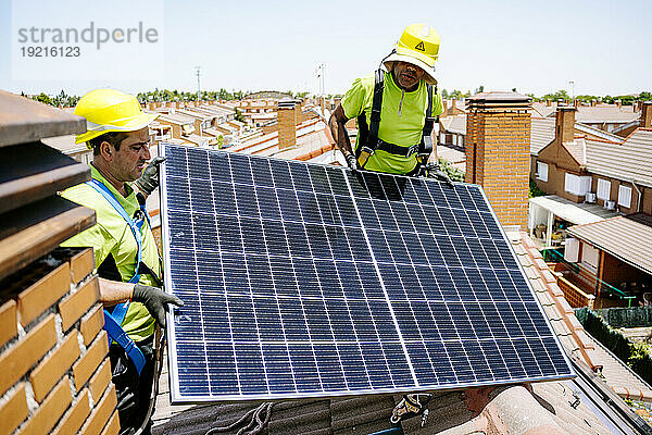 Ingenieure mit Schutzhelmen installieren an einem sonnigen Tag ein Solarpanel