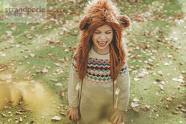 Happy girl wearing fur hat standing in garden