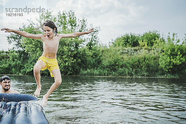 Fröhlicher Junge springt in den Fluss