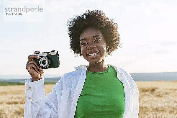 Happy young woman holding camera