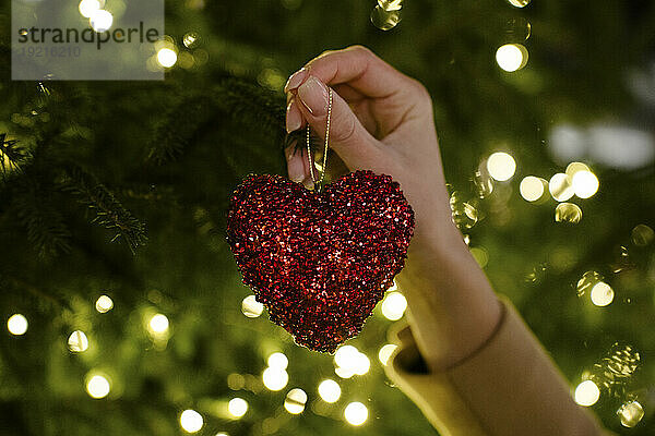 Hand of woman holding heart shaped Christmas decoration