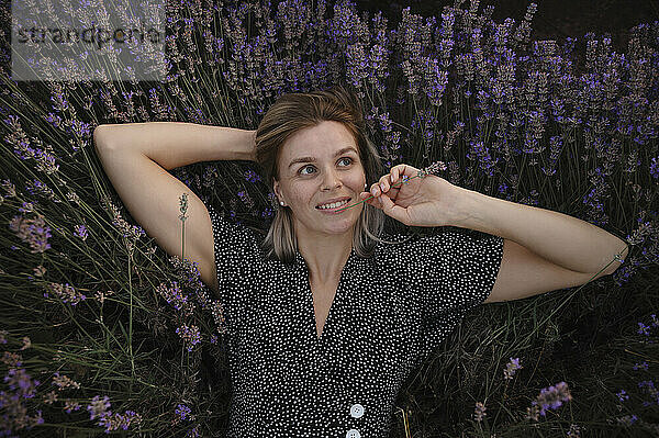 Thoughtful woman lying amidst lavender flowers
