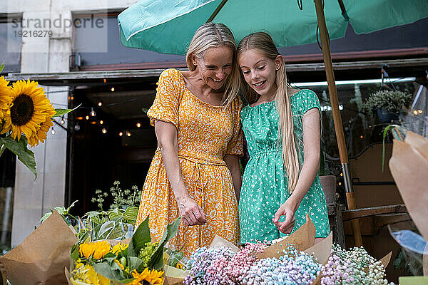 Glückliche Mutter und Tochter kaufen Blumen im Blumenladen
