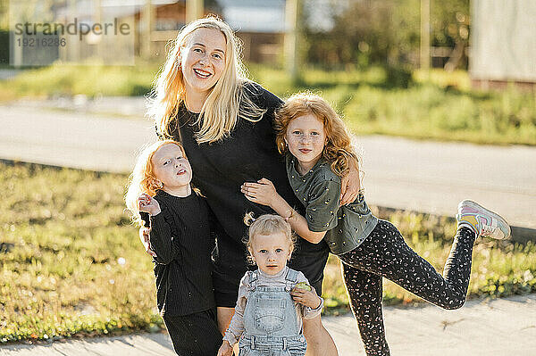 Lächelnde Mutter und Töchter im Park an einem sonnigen Tag