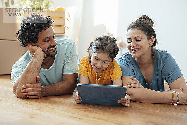 Glückliche Frau und Mann mit Tochter  die Tablet-PC auf dem Boden benutzen