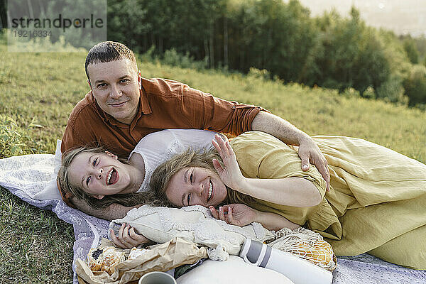 Glückliche Familie  die Spaß hat und auf einer Decke auf der Wiese liegt