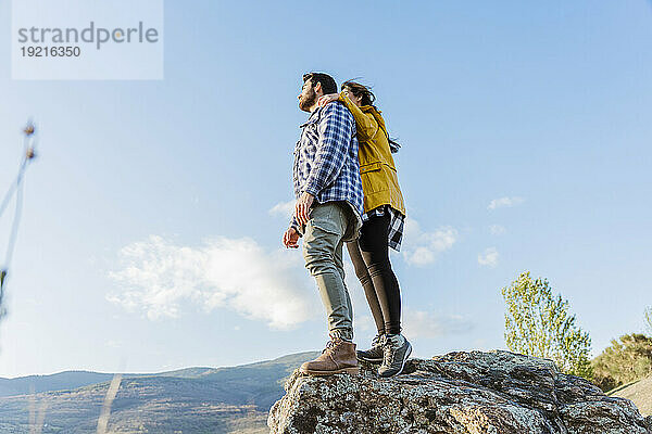 Couple standing on rock under sky