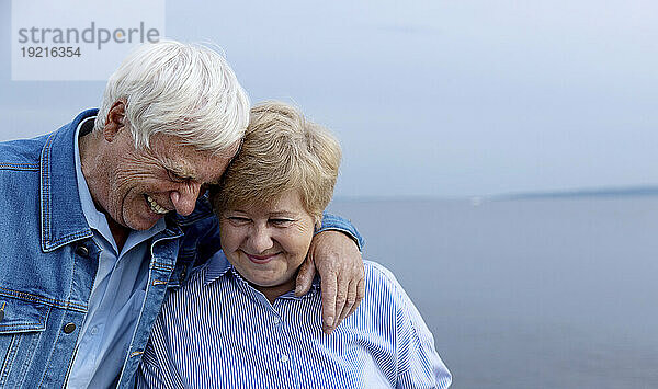 Smiling senior couple with arm around at beach