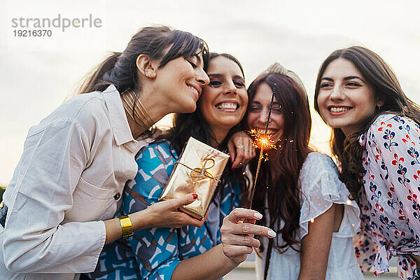 Cheerful friends with gift box and sparkler