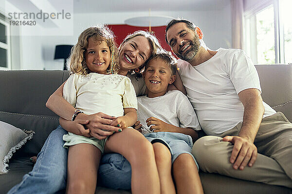 Glückliche Eltern mit Kindern  die zu Hause auf dem Sofa sitzen