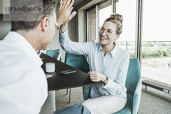 Glückliche Geschäftsfrau gibt einem Kollegen im Büro ein High-Five