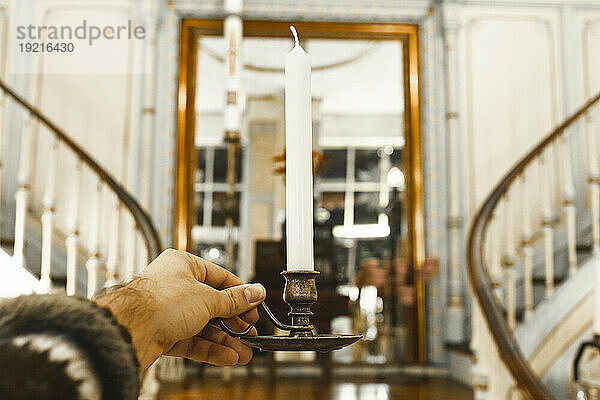 Hand of man holding candle at home