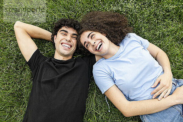 Young friends relaxing and laughing on grass