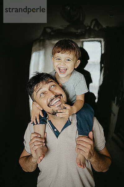 Smiling father carrying son at home