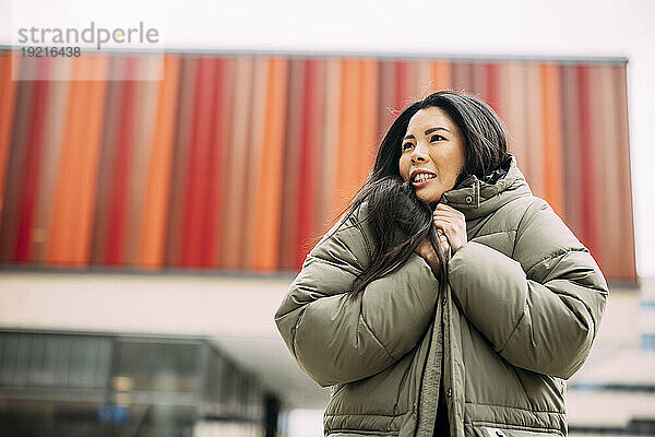 Schöne Geschäftsfrau trägt gepolsterte Jacke vor dem Bürogebäude