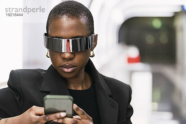 Junge Frau trägt eine intelligente Brille und benutzt ein Mobiltelefon