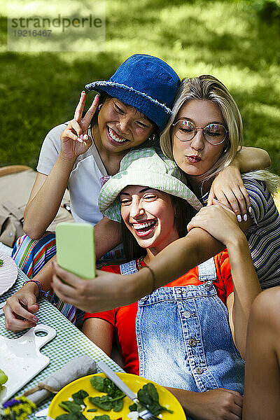 Glückliche Freunde machen Selfie mit Smartphone im Garten