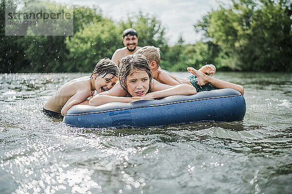 Verspielte Kinder auf Schlauchboot im Fluss
