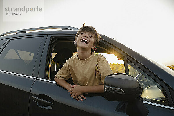 Cheerful boy leaning outside car window
