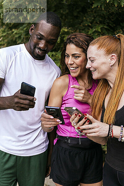 Aufgeregt Freunde teilen Smartphones im Park