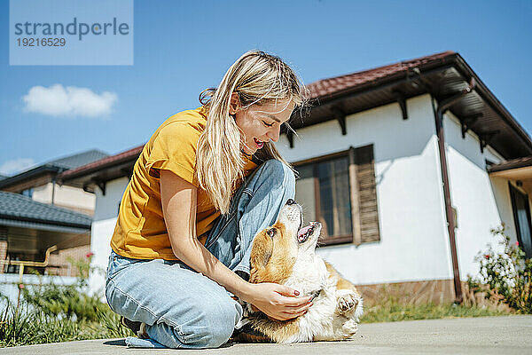 Glückliche Frau  die an einem sonnigen Tag mit Hund spielt
