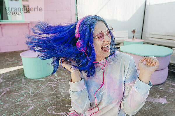 Glückliche Frau mit gefärbten blauen Haaren  die im Café Musik hört